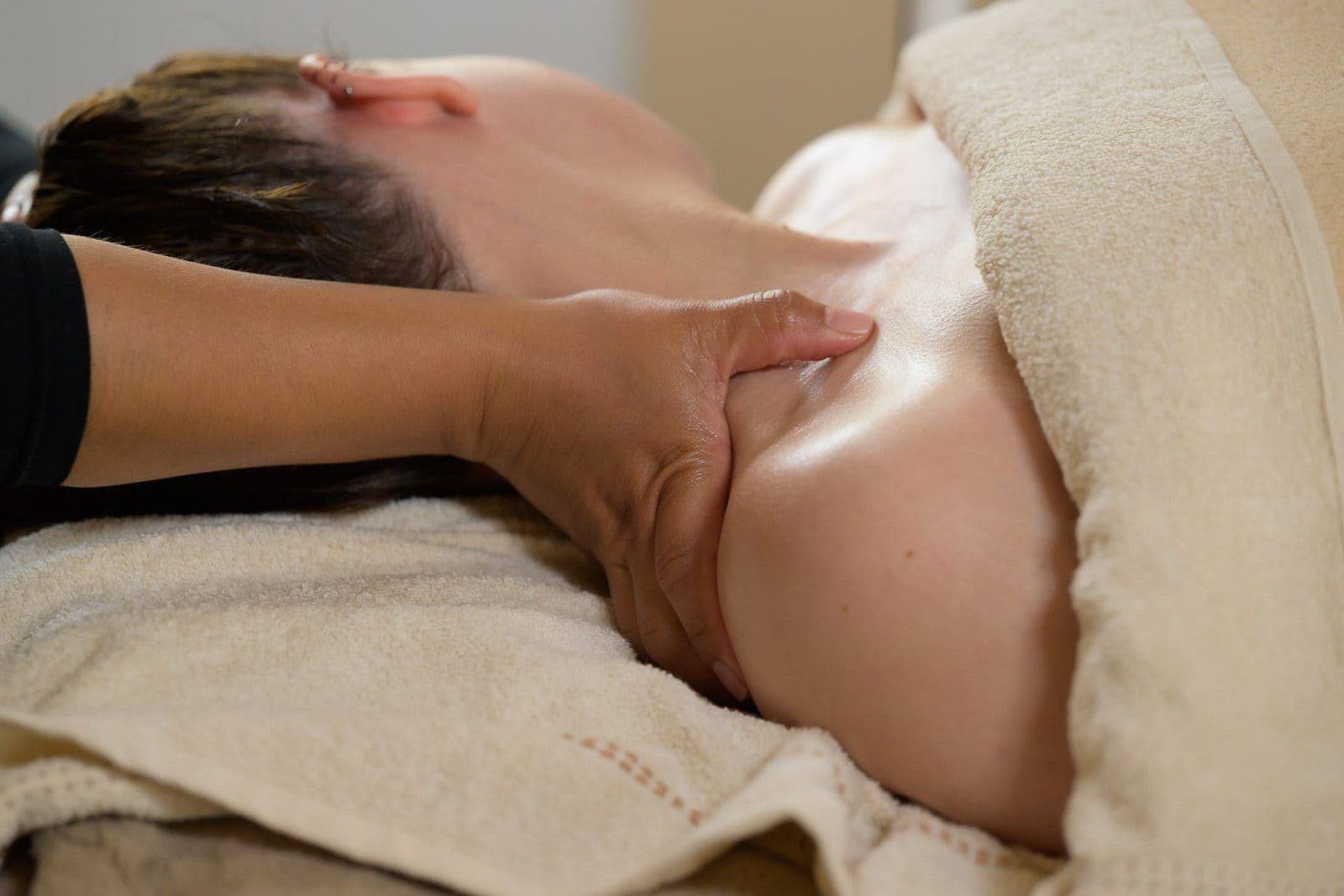 Shoulder massage in a salon, the practitioner's hands and a cream towel