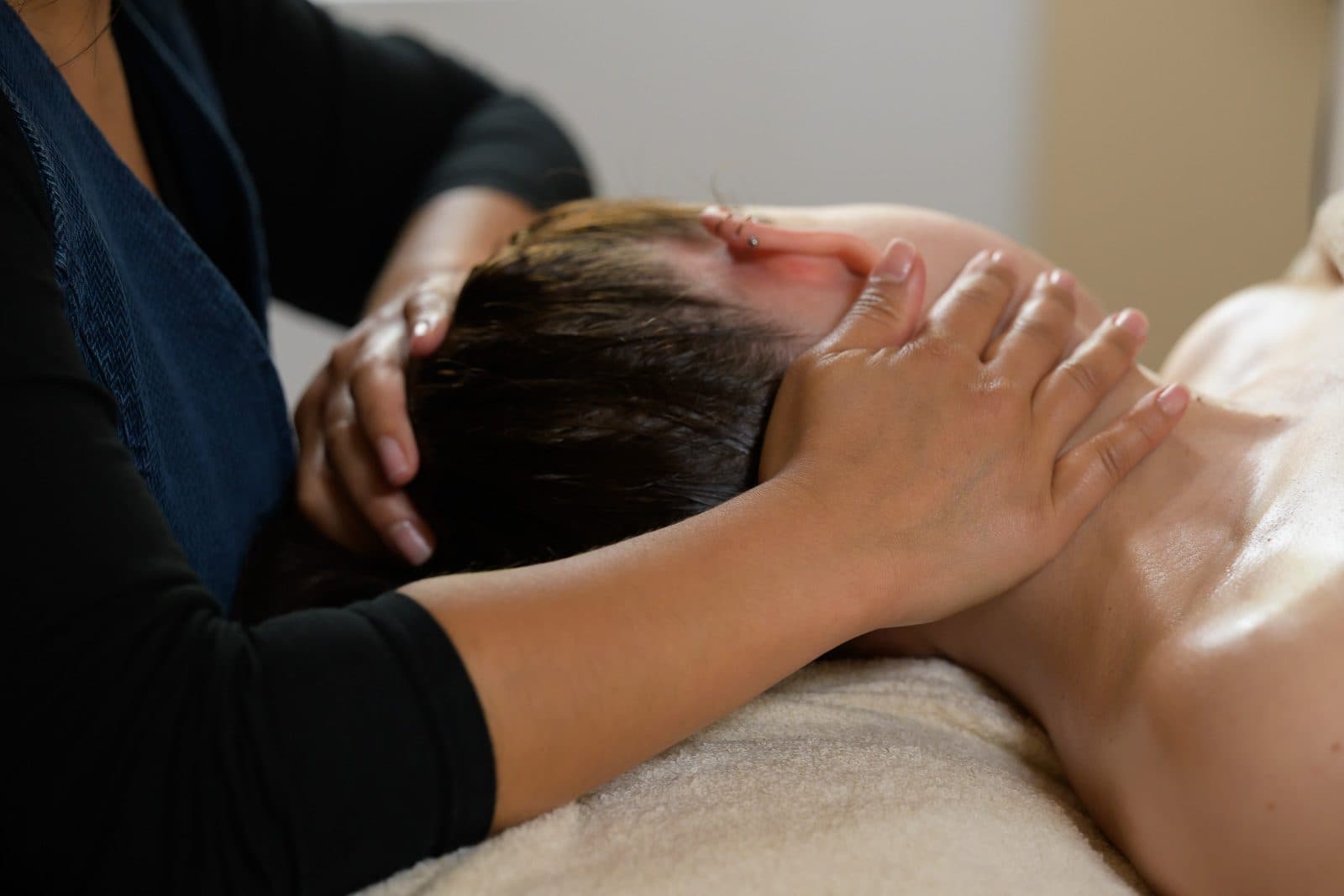 Facial massage in a salon, hands resting on the temples of a reclining client