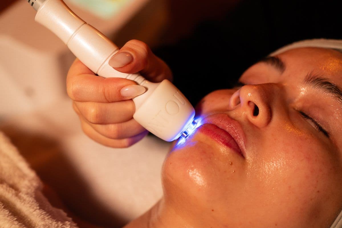 Soin du visage à la lumière LED bleue en cabine d'institut, gros plan sur l'appareil