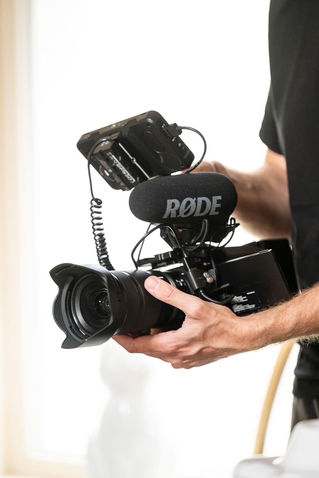 Hands holding a camera fitted with its microphone, backlit
