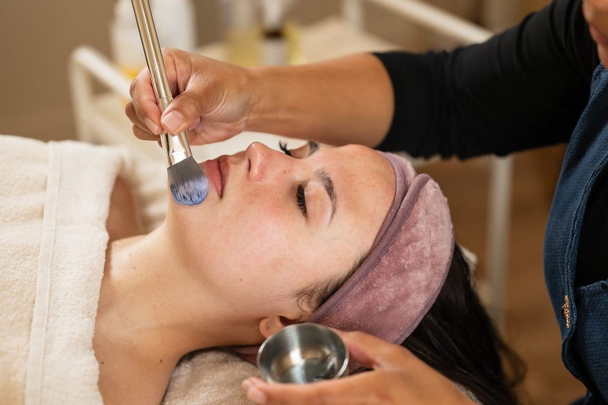 A mask being applied with a brush during a facial treatment in a salon