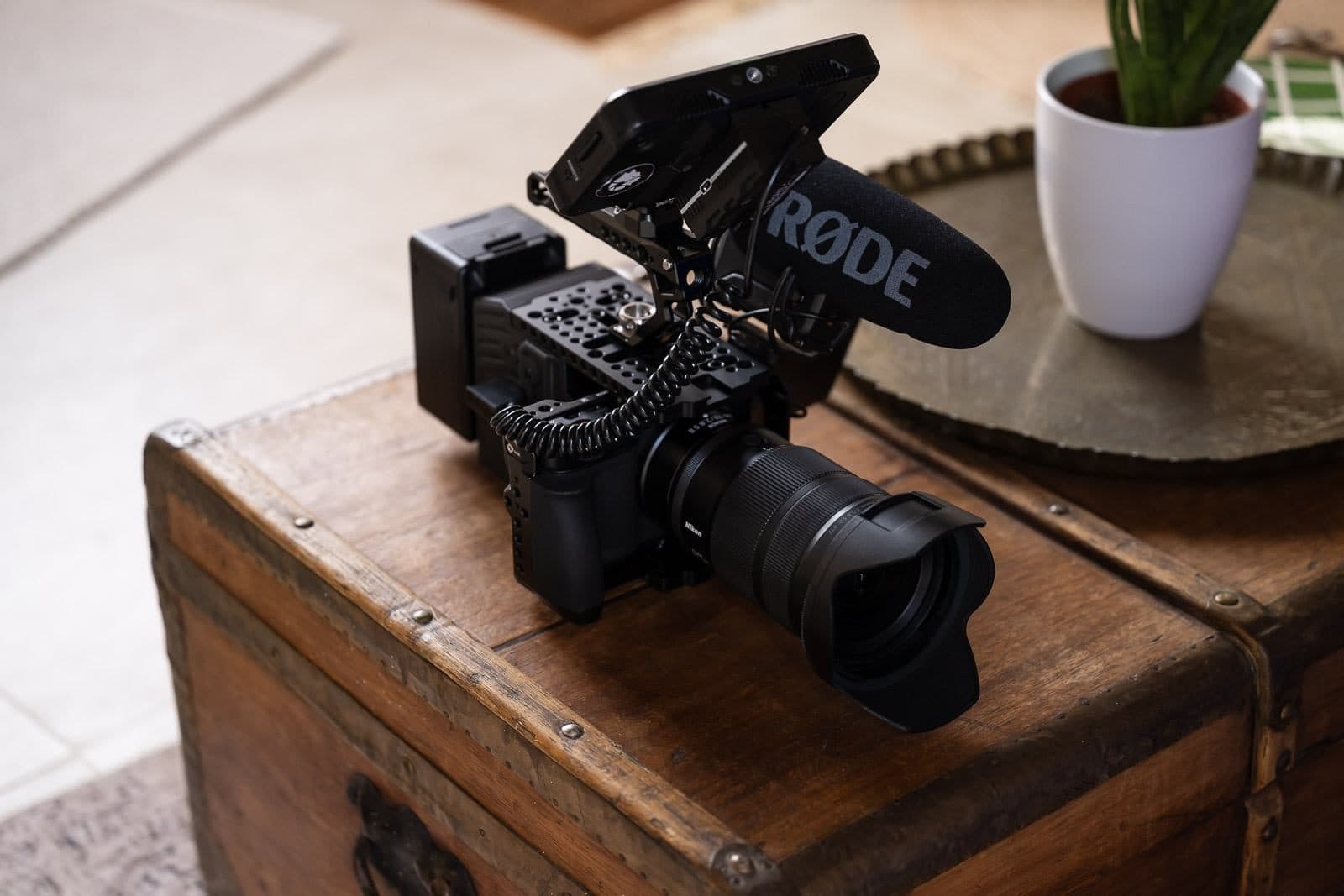 Film camera fitted with its microphone, resting on an antique trunk in a bright interior
