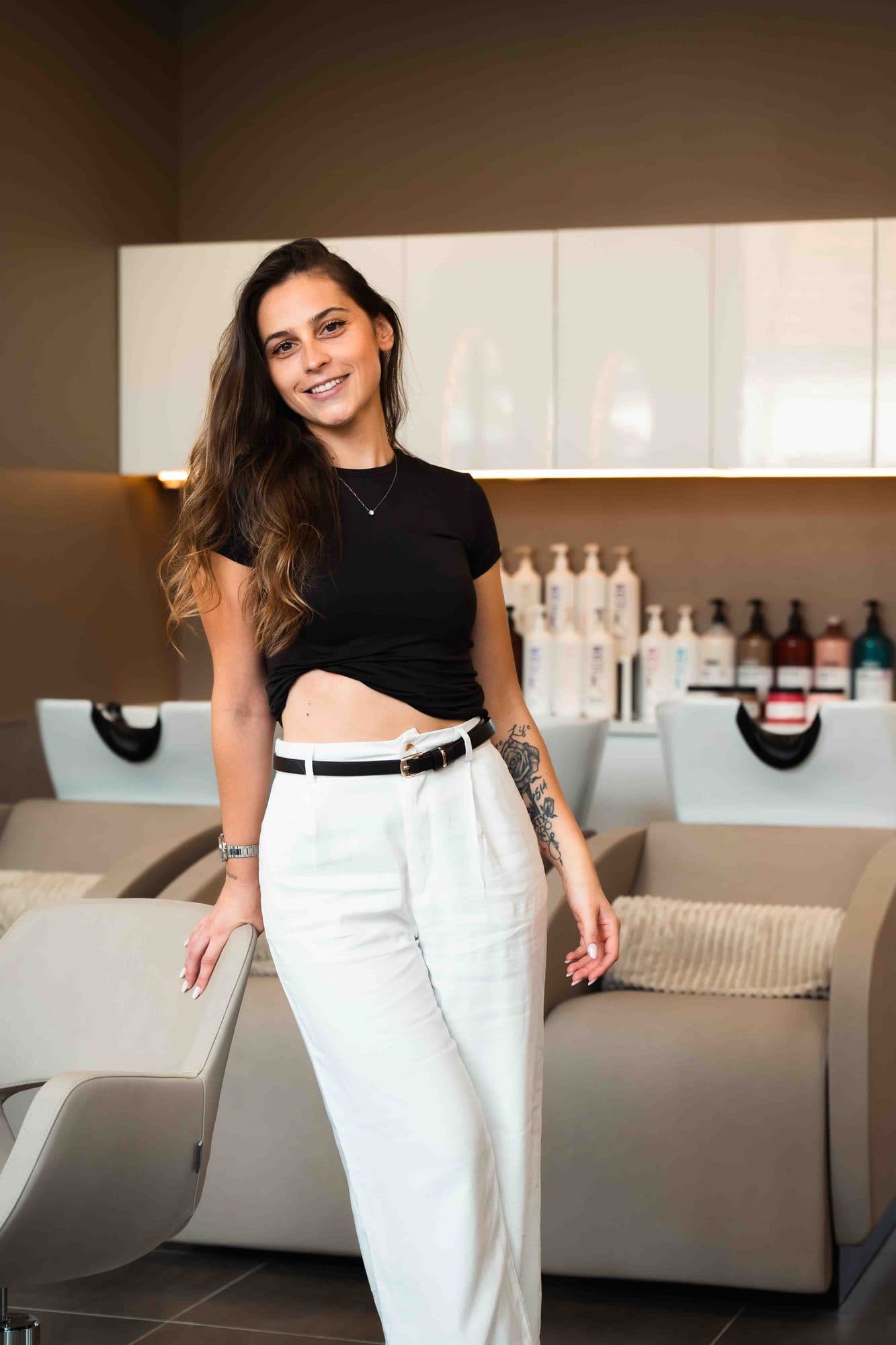 Aurélie, gérante du salon Aurea, debout dans son salon de coiffure aux miroirs en arche